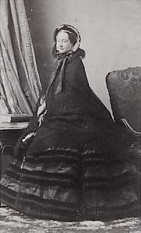 1860 Eugenie in crinoline, paletot, and bonnet looking at photographer