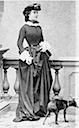 Sissi wearing an equestrian dress with a small dog